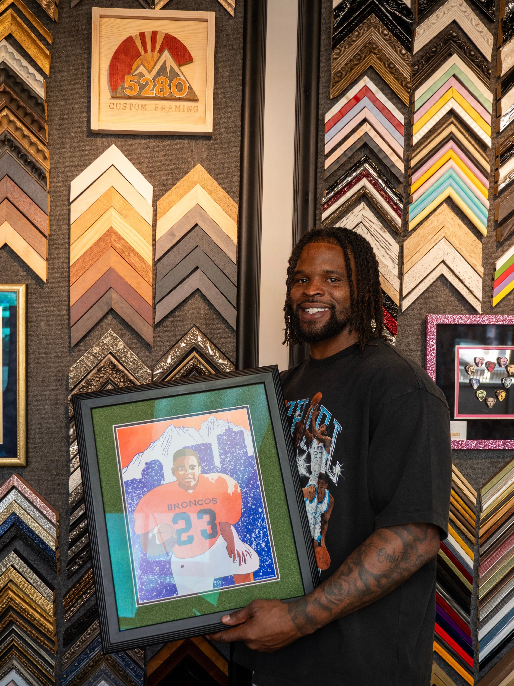 Dre Greenlaw with custom framed Broncos artwork at 5280 Custom Framing