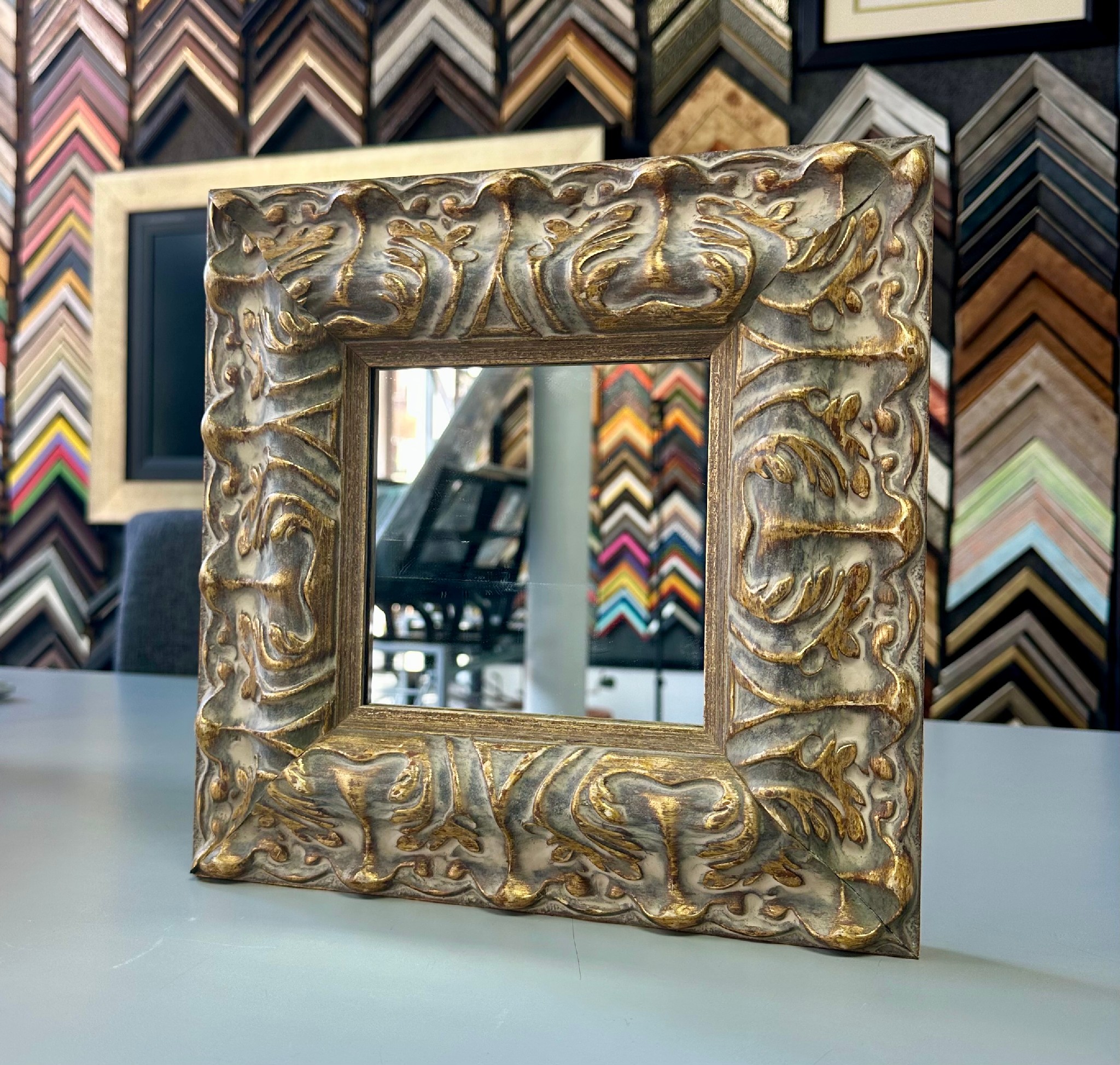 Custom framed mirror with an ornate antique silver and gold leaf frame featuring classic carved detailing